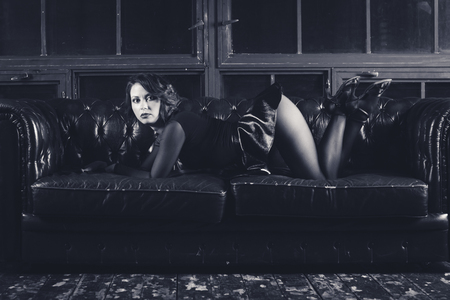 sexy blonde woman in long pink dress sitting on the couch. Black and white retro style photoの写真素材