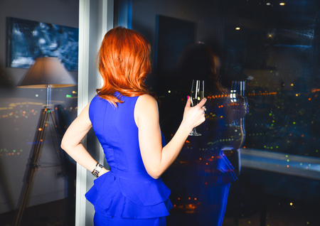 Elegant lady wearing evening dress sitting in the chair in the old vintage library. Beauty, fashion.の写真素材