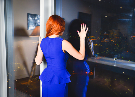 Elegant lady wearing evening dress sitting in the chair in the old vintage library. Beauty, fashion.の写真素材