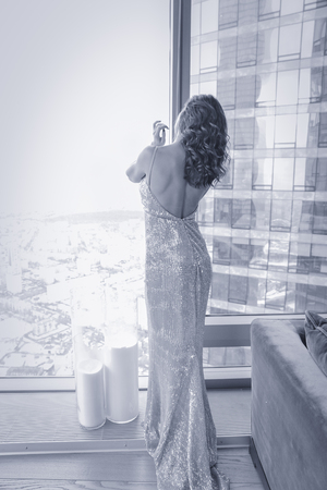 Elegant lady wearing evening dress sitting in the chair in the old vintage library. Beauty, fashion.の写真素材