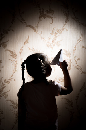 Happy kid playing with paper airplane in the sunsetの写真素材