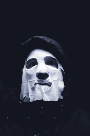 Maniac in white mask and hoodie showing fist, isolated on black backgroundの写真素材