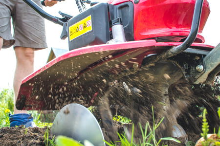 The unknown plows the earth with the help of a motor-block in springの写真素材