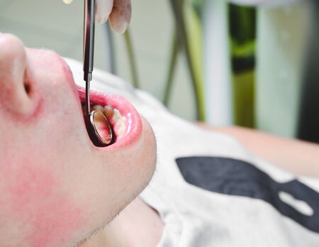 Patient at dentists office, getting her white teeth interdental spaces examined with hand-held...