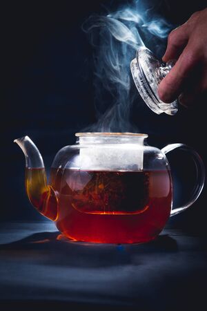 Process brewing tea,tea ceremony,Cup of freshly brewed black tea,warm soft light, darker background.の写真素材