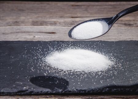 A pile of salt and a hand holding a silver spoonの写真素材