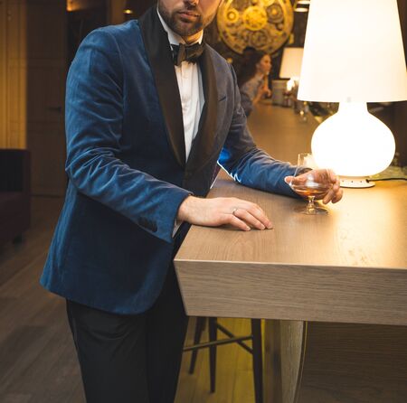 Handsome well-dressed man in jacket with glass of beverageの写真素材