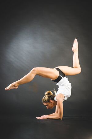 Gymnast girl doing splits in the air. Beautiful cool young fit gymnast woman in blue sportswear dress working out, performing art gymnastics element, jumping, doing split leap in the air, dancingの写真素材