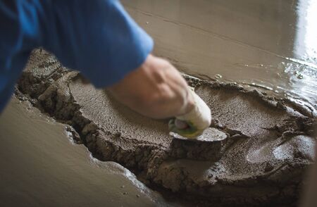 Employee performs sand and cement screed floor. Sand and cement floor screed