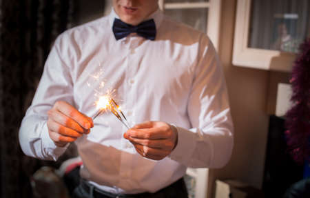 guy in a shirt and bow tie holding a sparklerの写真素材