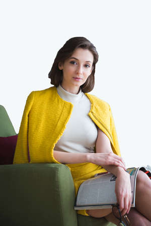 portrait of attractive woman with glasses and notebook sitting on a chair isolated on whiteの写真素材