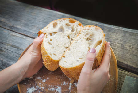 Baker woman holding homemade rustic wheat bread in hands. Selective focus.の写真素材
