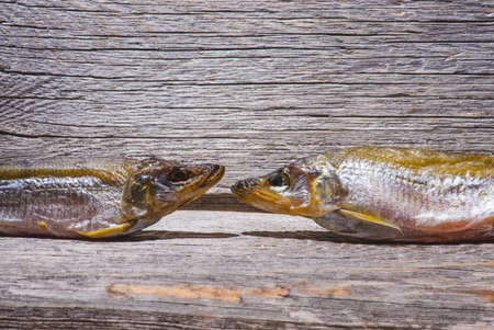Smoked or dried smelt fish on a wooden Board on a brown wooden table. Top view with space for textの写真素材
