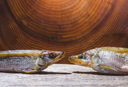 Smoked or dried smelt fish on a wooden Board on a brown wooden table. Top view with space for textの写真素材