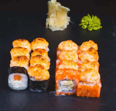 Sushi rolls california with snow crab, cream cheese, cucumber, sesame seeds and masago caviar on black background with reflection. Sushi menu, japanese cuisine.の写真素材