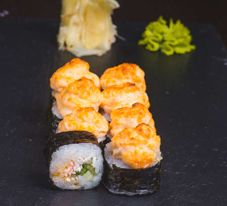Sushi rolls california with snow crab, cream cheese, cucumber, sesame seeds and masago caviar on black background with reflection. Sushi menu, japanese cuisine.の写真素材