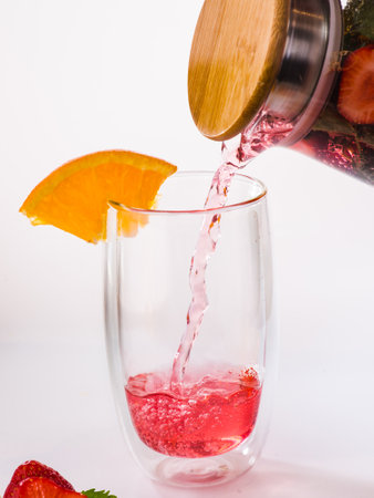 water from jug pouring into glass on wooden table outdoorsの写真素材