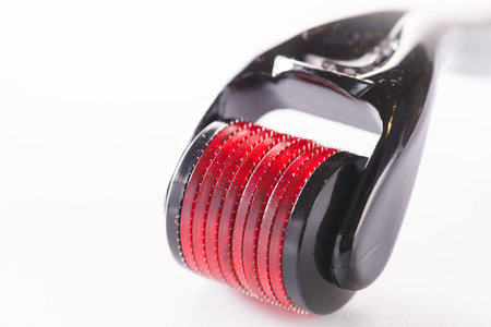 Dermaroller - Beauty treatment, mesotherapy or medical collagen production stimulation and micro needling therapy concept titanium pink and black derma roller isolated on white backgroundの写真素材