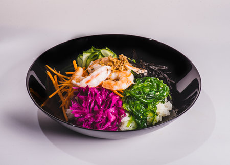 Fresh seafood recipe. Shrimp salmon poke in bowl on black wooden table backgroundの写真素材