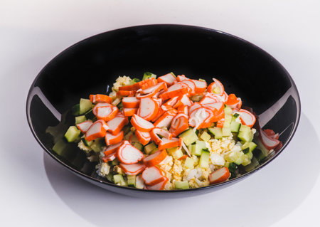 Russian style imitation crab salad with crab sticks, corn, eggs, cucumber and rice. White background, top view, flat layの写真素材