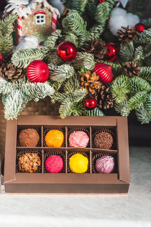 Chocolates in a red festive box dark chocolate truffle on a Christmas background with New Year's toys balls fir branches. flat mock up copy space.の写真素材