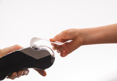 Close-up of a woman's hand tearing a check from the cash register next to a cart with wrapped boxes...