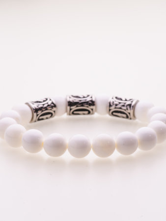 A charming double bracelet in shades of pink, made from natural stone and set against a gray background. The heart charm stands out in this close-up top viewの写真素材