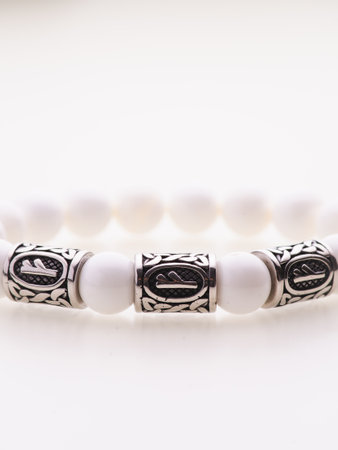 A charming double bracelet in shades of pink, made from natural stone and set against a gray background. The heart charm stands out in this close-up top viewの写真素材