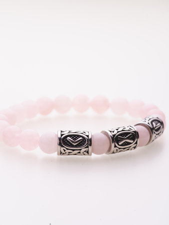 A charming double bracelet in shades of pink, made from natural stone and set against a gray background. The heart charm stands out in this close-up top viewの写真素材