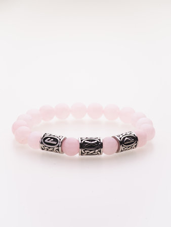 A charming double bracelet in shades of pink, made from natural stone and set against a gray background. The heart charm stands out in this close-up top viewの写真素材
