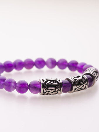 A charming double bracelet in shades of purple, made from natural stone and set against a white background. The intricate silver details stand out in this close-up viewの写真素材