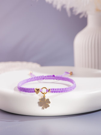 Purple bracelet with heart and four-leaf clover charms, isolated on white background.の写真素材