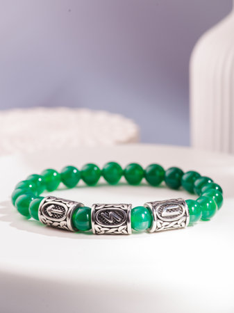 White bracelet made of natural kohalong stone on a woman's hand against a blue sky. Texture of pearl agate close-up. High quality photoの写真素材