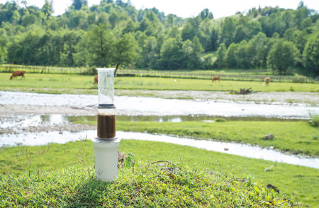 barista hand pouring filter coffee in cup with kettle outdoors in natureの写真素材