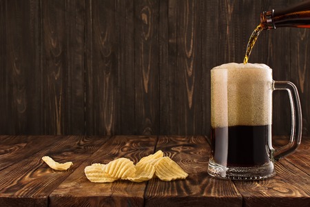 Glass with a dark beer on a wooden tableの写真素材