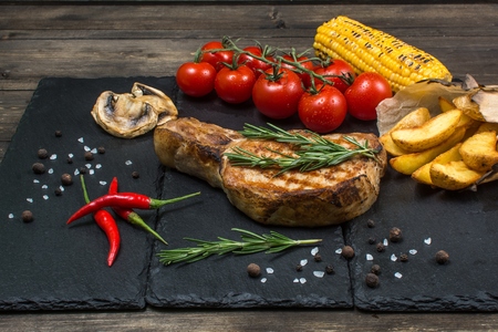 Grilled sliced beef steak with rosemary and tomatoes, on a wooden tableの写真素材