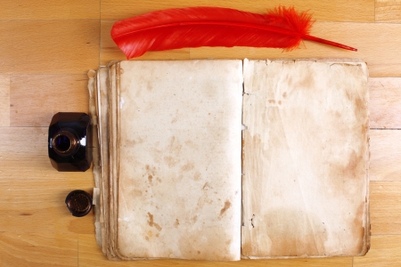 vintage book with red feather pen and inkwell on tableの写真素材