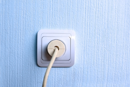 Electrical plug and outlet connector in blue wallの写真素材