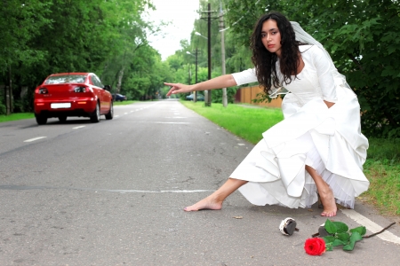 beautiful bride hitch-hike at the roadの写真素材