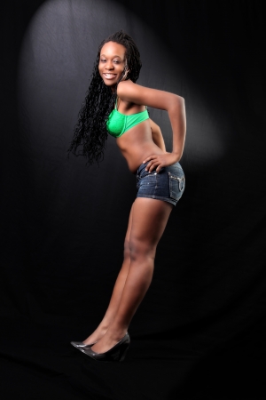 young afro-american woman in bra and shorts against black backgroundの写真素材