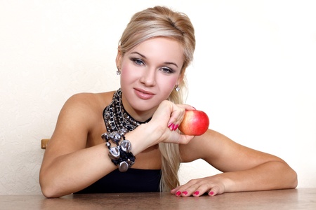 woman with red apple against yellow wall at tableの写真素材