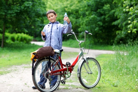 Young boy with bicycle with clear water relaxing outdoorsの写真素材