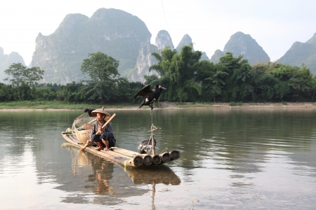 YANGSHUO - JUNE 18: Chinese man fishing with cormorants birds in Yangshuo, Guangxi region, traditional fishing use trained cormorants to fish, June 18, 2012 Yangshuo in Guangxi, Chinaのeditorial素材