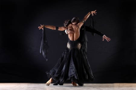 Latino dancers in ballroom against on black の写真素材