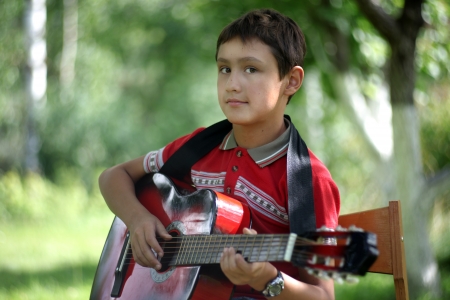 boy playing the guitar outdoors 