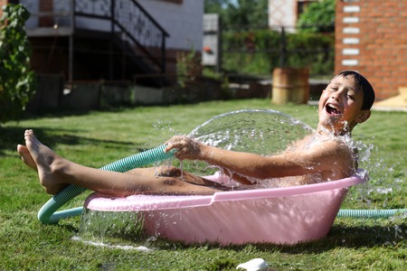 boy with splash water in hot summer day outdoorsの写真素材