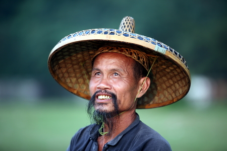 GUANGXI - JUNE 18: Chinese man in old hat in Guangxi region, traditional type of man face in China, June 18, 2012 in Guangxi, China. The average life expectancy among Chinese men is 72 yearsのeditorial素材