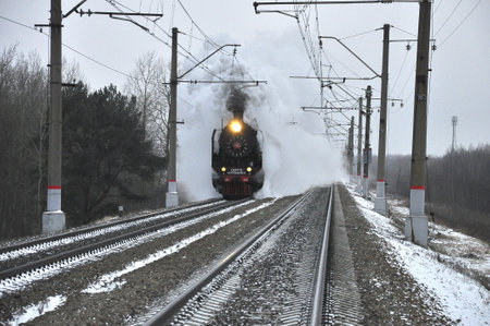 An old smoking locomotive running on rails.