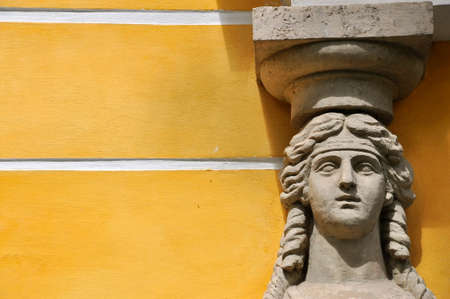 High-relief face of an antique woman against a yellow wall.の写真素材