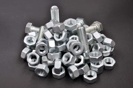 Pile of fasteners. Bolts, nuts, screws, on a black background.